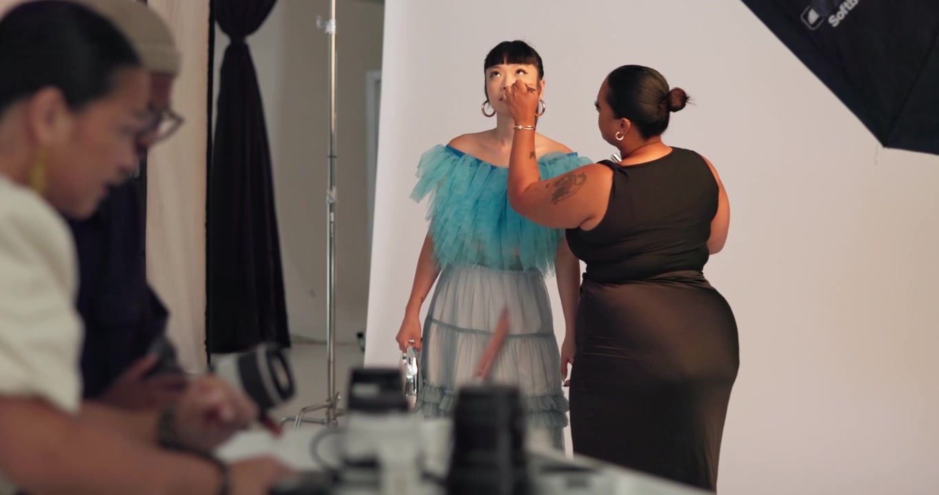 Truccatrice che applica il trucco a una modella durante un servizio fotografico professionale
