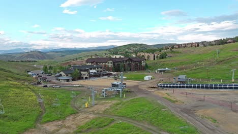 aerial trucking pan over ski chair lift and winding dirt road in ski resort during summer in mountains of colorado