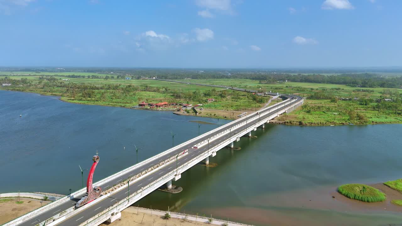 Aerial view of large bridge on the large river with greenery landscape of plantation. Bridge on the Indonesian countryside. 4K drone shot.
