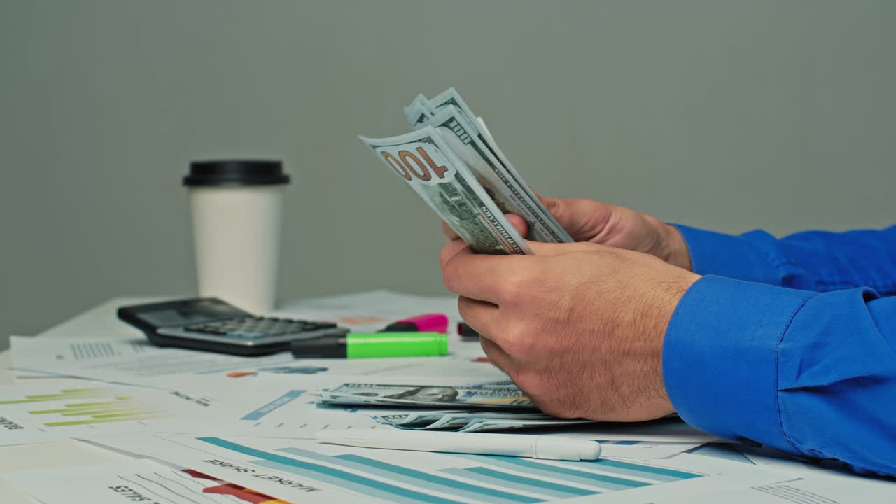 Gerente masculino irreconocible contando dinero en efectivo. Empresario de empresa financiera con dólares estadounidenses. Ingresos y gastos del hombre, pago de préstamo, documentos, facturas, recibos de servicios públicos sobre la mesa, primer plano. Concepto de gestión de presupuesto familiar