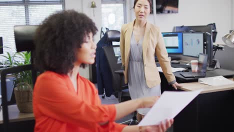 diverse businesswomen talking and holding documents in office, slow motion