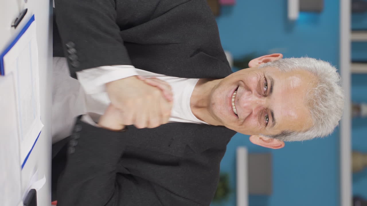 video vertical de un trabajador de oficina en casa mirando a la cámara aplaudiendo y emocionándose.