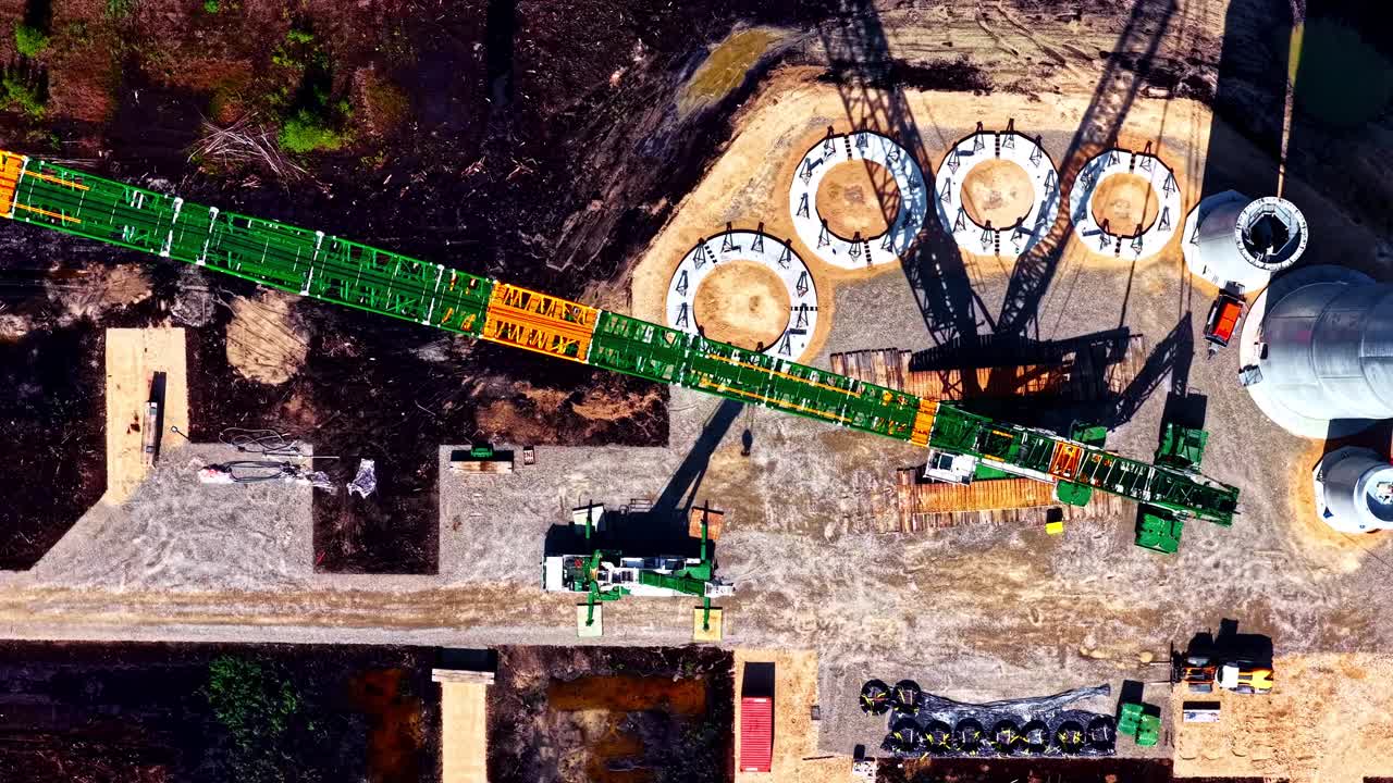 Wind turbine bases and towers being erected for clean, efficient energy - straight down sliding aerial view
