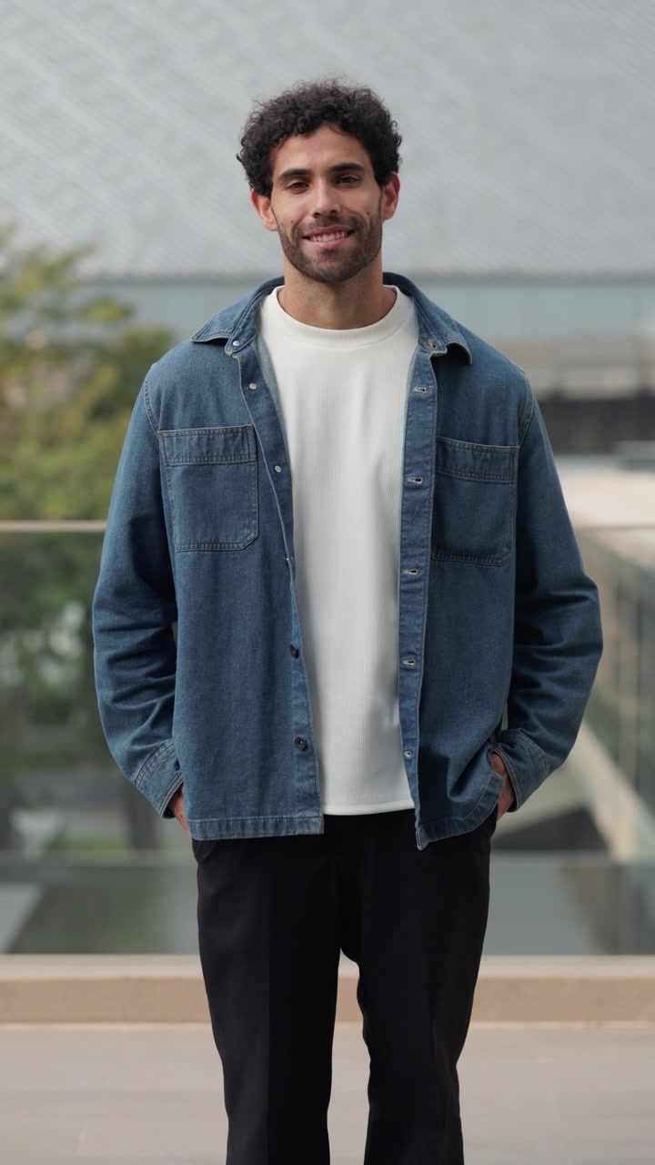 Giovane sorridente in piedi all'aperto con giacca di jeans