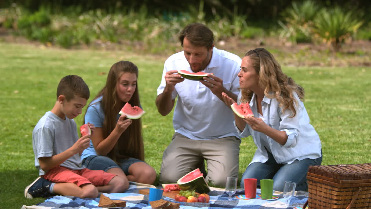 familia comiendo una sandía mientras tienen un picnic