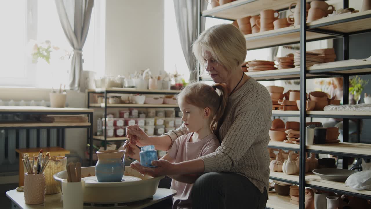 할머니는 손녀에게 도자기 회전 바에서 일하는 법을 가르니다.