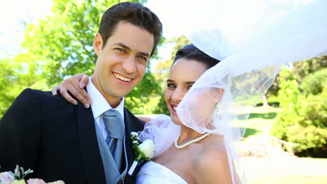 recién casados felices de pie en el parque