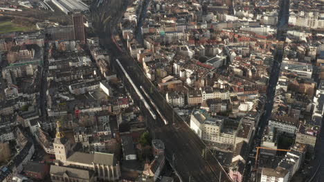 Aerial-static-shot-of-town-development-in-urban-neighbourhood-at-golden-hour.-Trains-slowly-moving-on-wide-multitrack-railway-line.-Cologne,-Germany