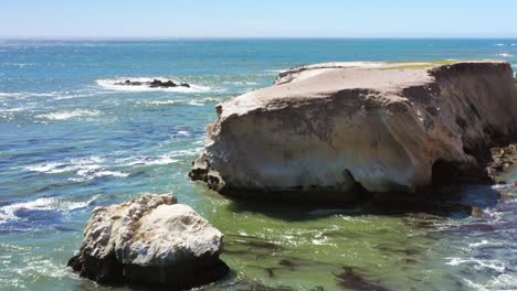 a rocky ocean coast with waves rolling in to the cliffs - slow motion panning view