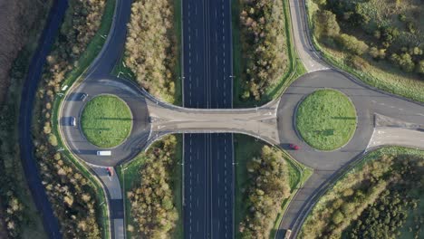 Rising-aerial:-Vehicles-drive-on-highway-roundabouts-over-motorway