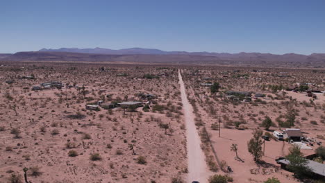 joshua tree california car driving down dirt road with houses in desert