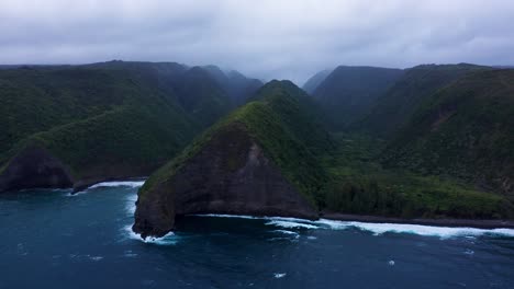 towering emerald cliffs plunge into dark blue waves, wrapped in drifting mist and crowned by heavy clouds for a wild, untouched coastal scene.