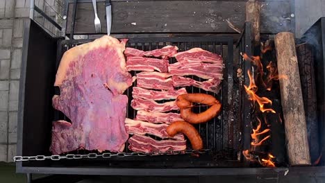 Vertical-view-of-a-black-barbecue-with-meat-cooking-on-fire-on-a-sunny-day