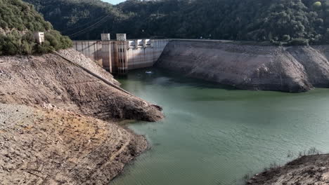 Aerial-flying-over-Ter-River-towards-Sau-reservoir-dam,-low-water-level,-Catalonia