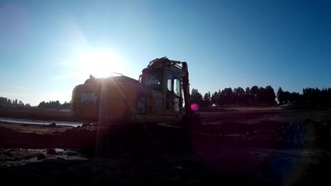 yellow excavator works with bucket to clear mud sludge and debris from the bottom of the drained river