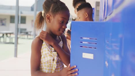 Video-portrait-of-happy-african-american-schoolgirl-using-locker-at-school