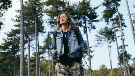 woman-walks-through-the-forest,-tall-pines