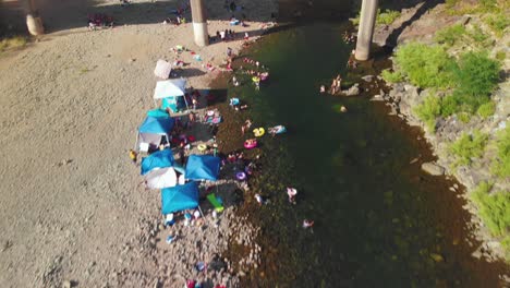 vista de cerca de un puente que cruza el pozo de natación auburn en el río americano en california - rodeado de árboles verdes y lleno de gente nadando y disfrutando su fin de semana de verano