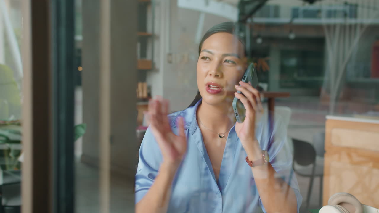 Asian Woman Consulting Clients on Phone Indoors