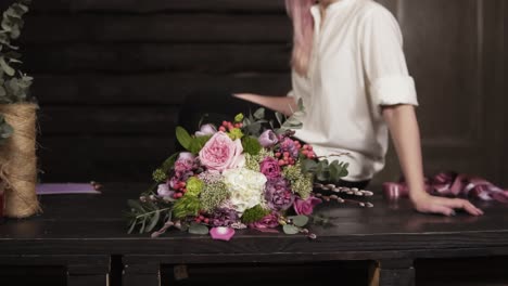 beautiful slow motion footage of an amazing bouquet made by professional florist. seductive, smiling girl in white shirt is sitting on the table. studio