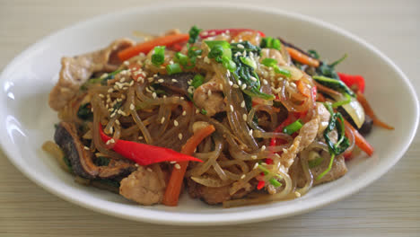 japchae or stir-fried korean vermicelli noodles with vegetables and pork topped with white sesame - korean traditional food style