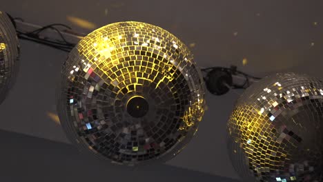 two disco balls hanging from the ceiling reflecting party light in a hotel lounge