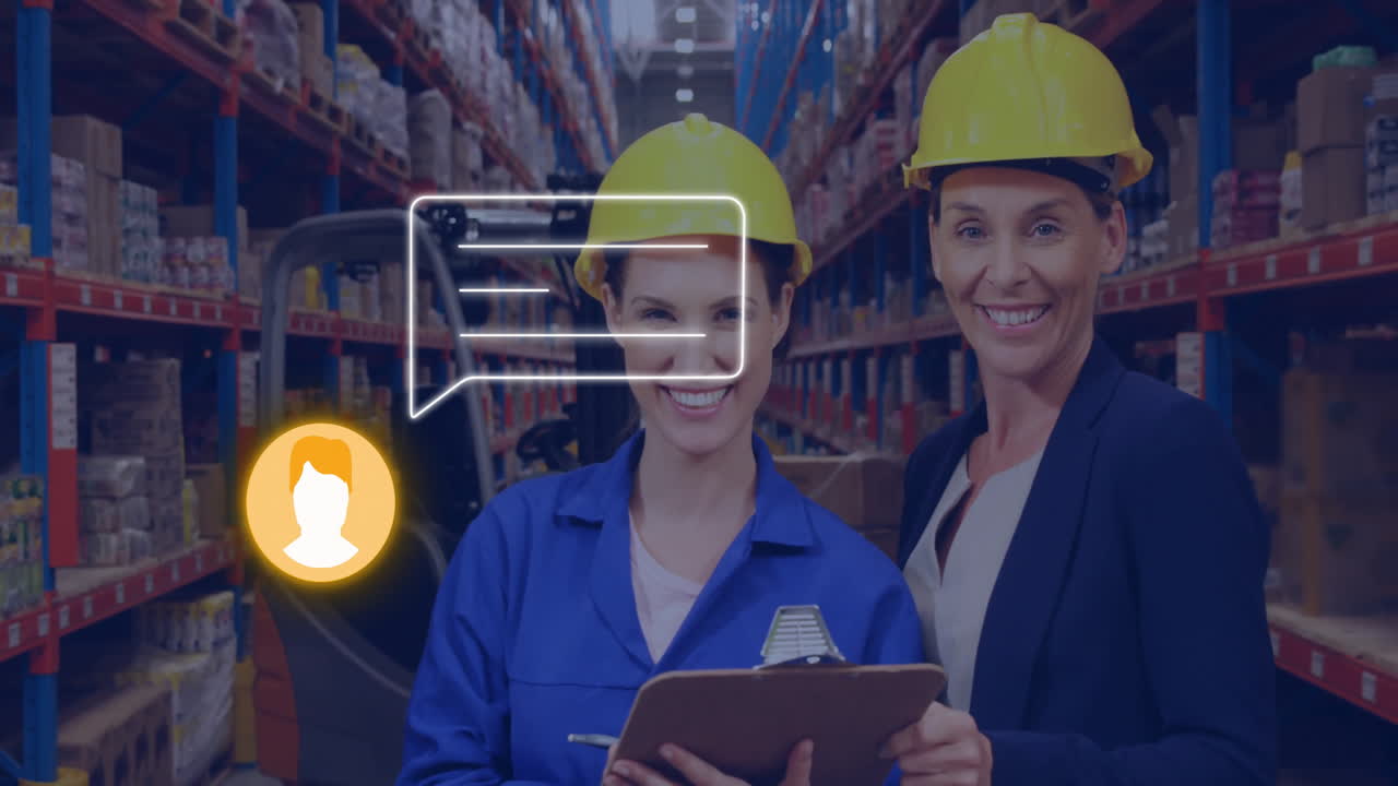 Two women in hard hats smiling in warehouse with chat icon animation