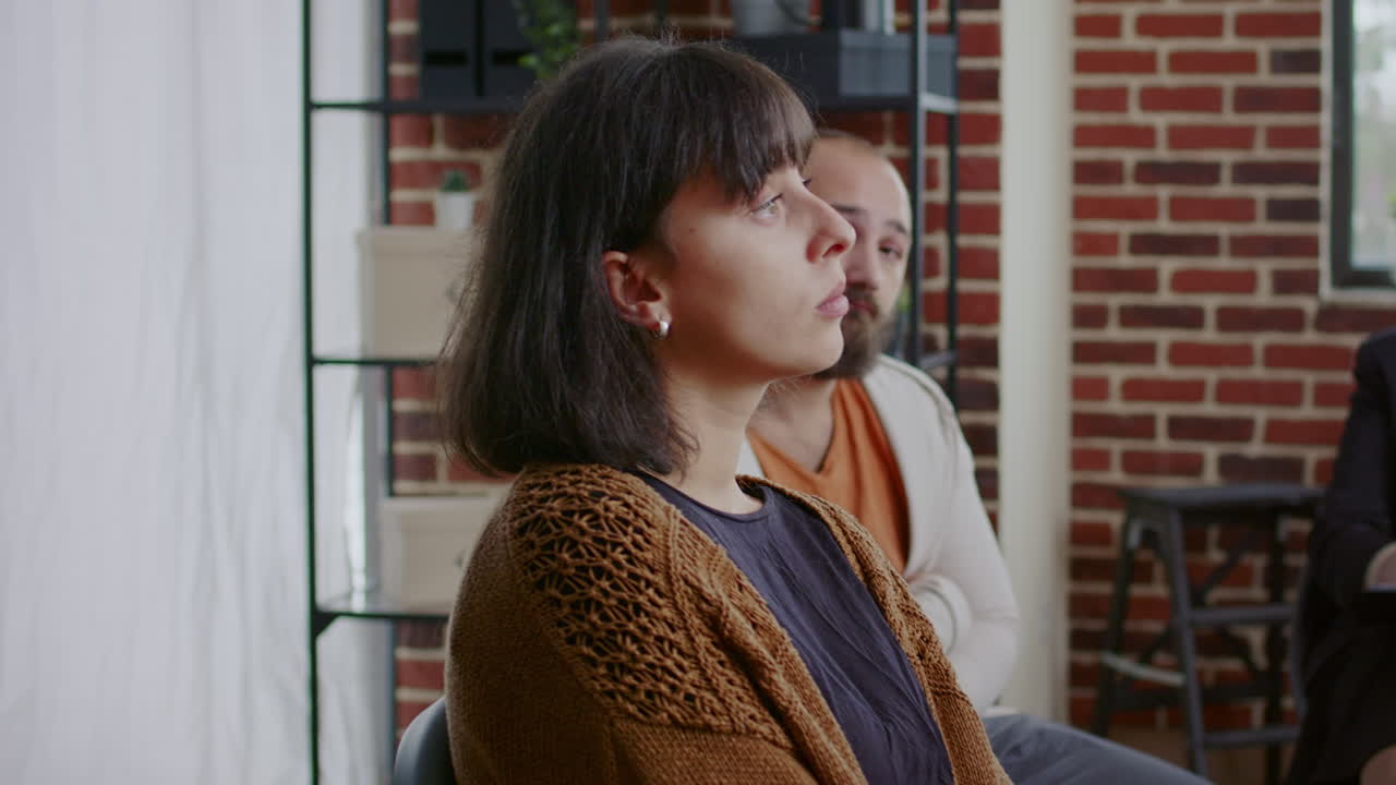 Woman sharing sad story with people and psychologist at aa group therapy session