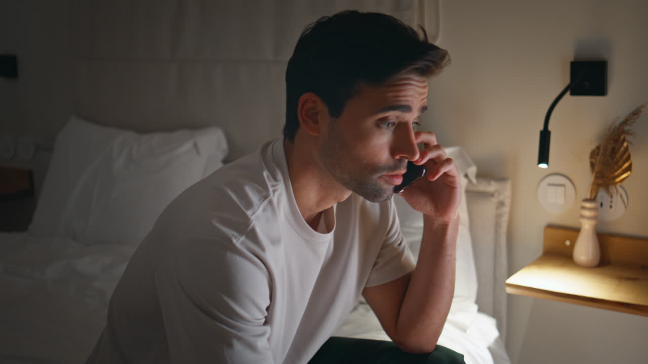 Man talking late call by smartphone sitting bed closeup. Male speaking cellphone