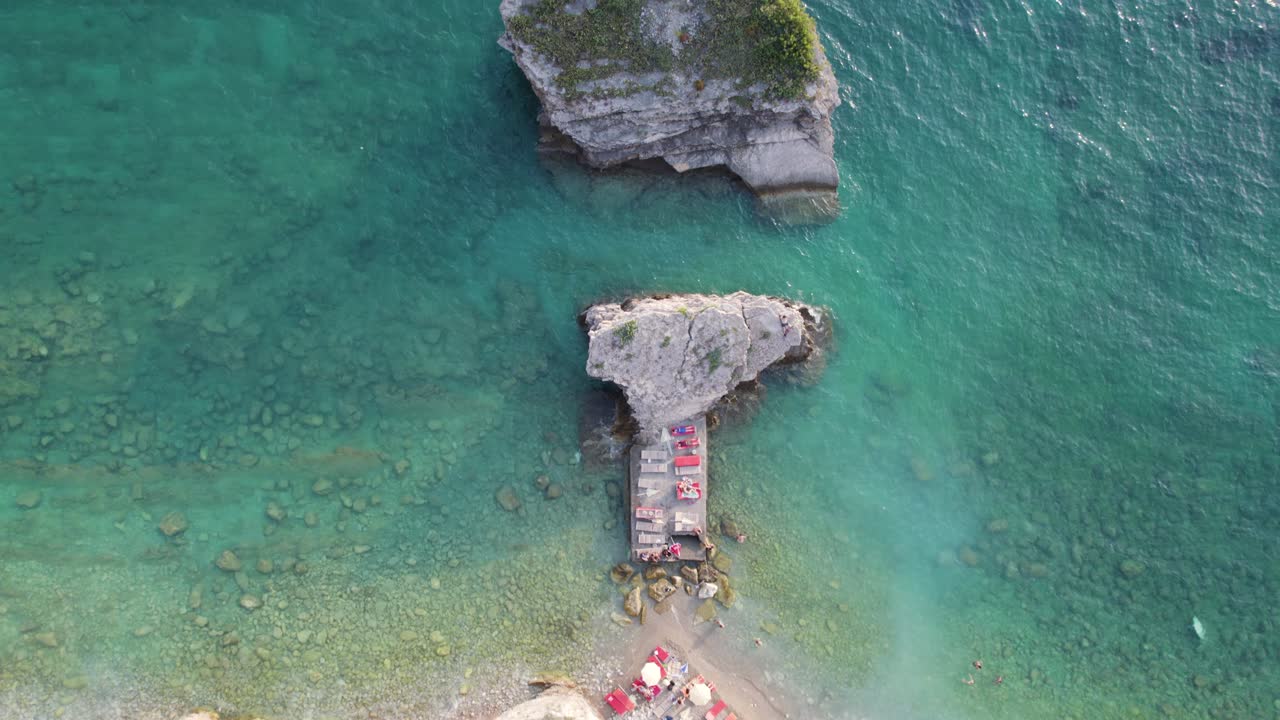 Turquoise sea and beach with sunbeds on Sveti Nikola Island in Montenegro, bird's eye view
