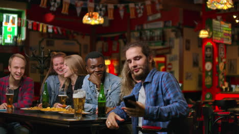 En-El-Bar-O-Restaurante,-Un-Hombre-Hispano-Se-Toma-Un-Selfie-De-Ella-Y-De-Sus-Mejores-Amigos.-Grupo-De-Jóvenes-Hermosos-En-Un-Establecimiento-Elegante.