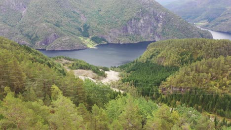 high voltage power lines passing in front of camera with bolstadfjord and road to voss in background - aerial from vaksdal mountains with road and piping to markaani powerplant seen in valley below