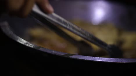 foto de un vendedor ambulante cocinando su comida indonesia para venderla friéndola en un tazón de aceite de cocina