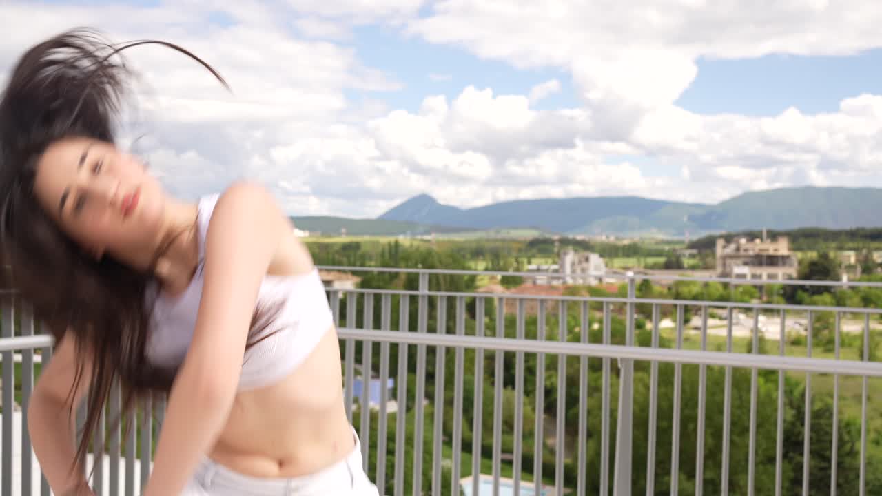 Woman dancing on balcony with scenic background