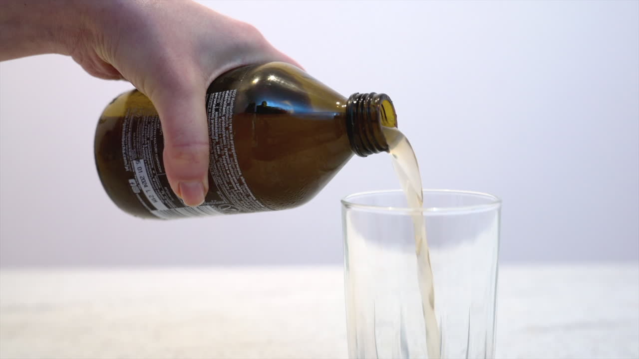 Close up of a woman pouring kombucha in a glass