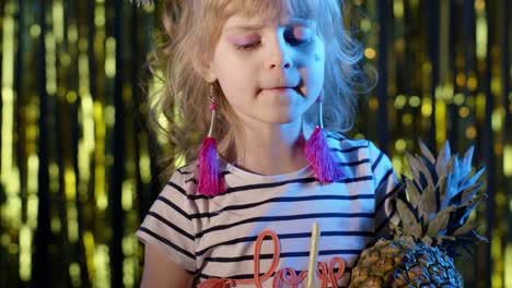niño a la moda con frutas de piña bebiendo jugo en un club futurista con luz de neón