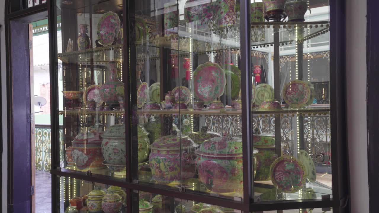 Colourful Flowers On The Round Table And Beautiful Ceramic Potteries Inside The Glass Shelf At Pinang Peranakan Mansion In Penang Malaysia - Panoramic Shot