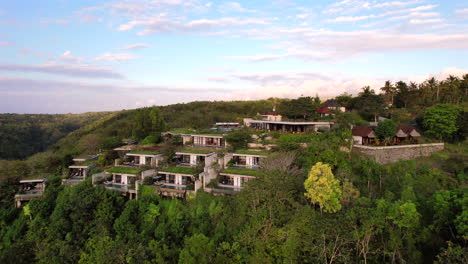 Aislado-Complejo-Eco-isla-Y-Hotel-En-Las-Montañas-De-Bali-Indonesia-Al-Atardecer-Con-Un-Pintoresco-Cielo-De-Algodón-De-Azúcar-Y-Nubes,-Vista-Aérea