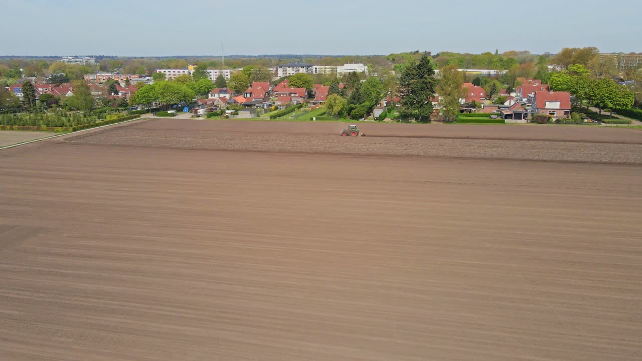 antena de un tractor arando una parcela de tierra en el borde de una pequeña ciudad
