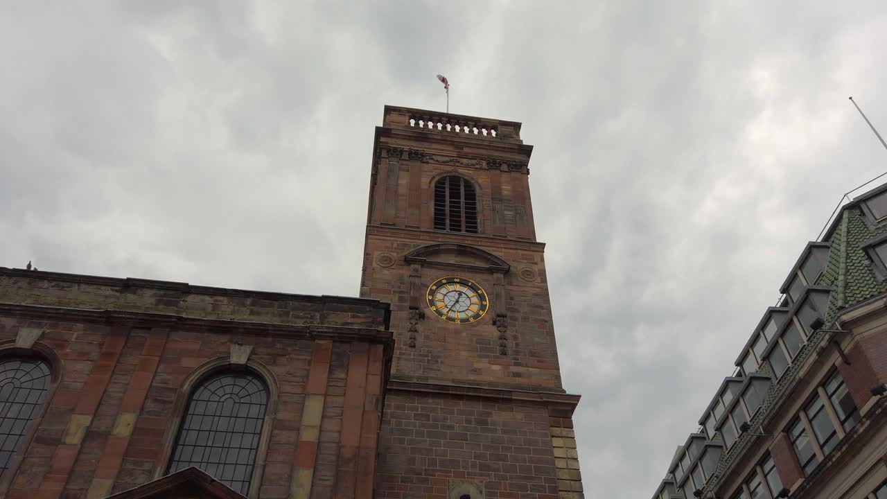 Manchester, UK St Ann's Church with English flag waving in the wind on a cloudy day