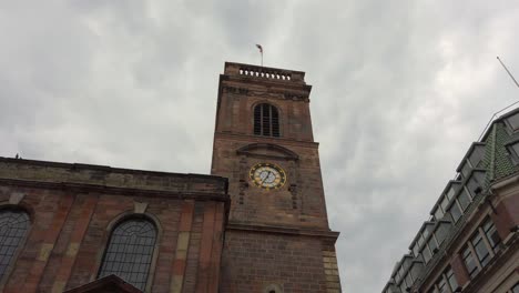 manchester, uk st ann's church with english flag waving in the wind on a cloudy day