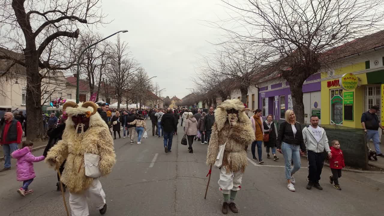 Daytime street view of the Busó-walking festival, as the locals walk among the visitors wearing sheepskin costumes and terrifying carved wooden masks in Mohacs, Hungary.