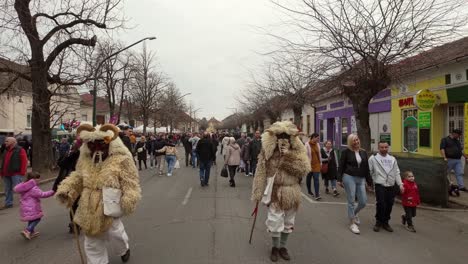 daytime street view of the busó-walking festival, as the locals walk among the visitors wearing sheepskin costumes and terrifying carved wooden masks in mohacs, hungary.