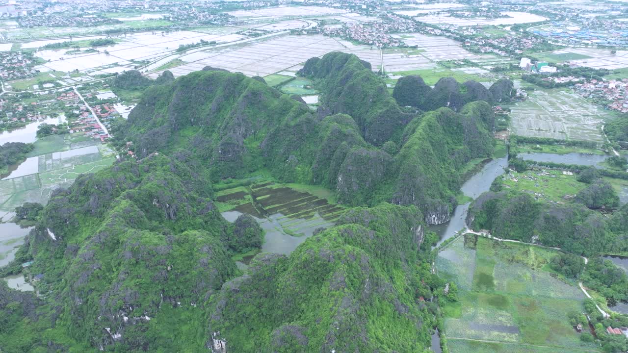 Lush green karst mountains and rice fields in Ninh Binh, Vietnam, peaceful aerial view