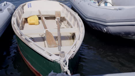 a small boat with paddles gently rocks in waves at the dock