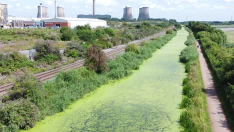 green algae covered canal waterway leading to power station industry aerial drone view slow dolly right