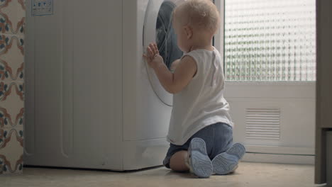 niño curioso mirando la lavadora en casa