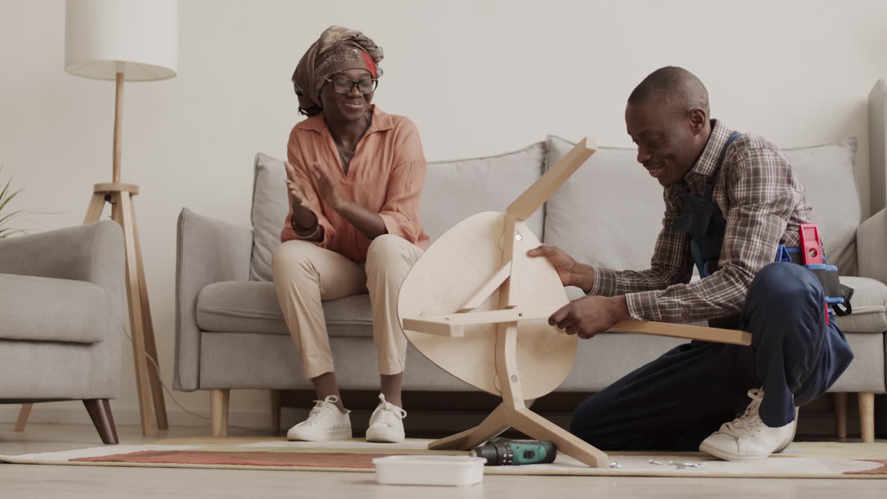 Carpenter Helping African-American Housewife Assembling Furniture