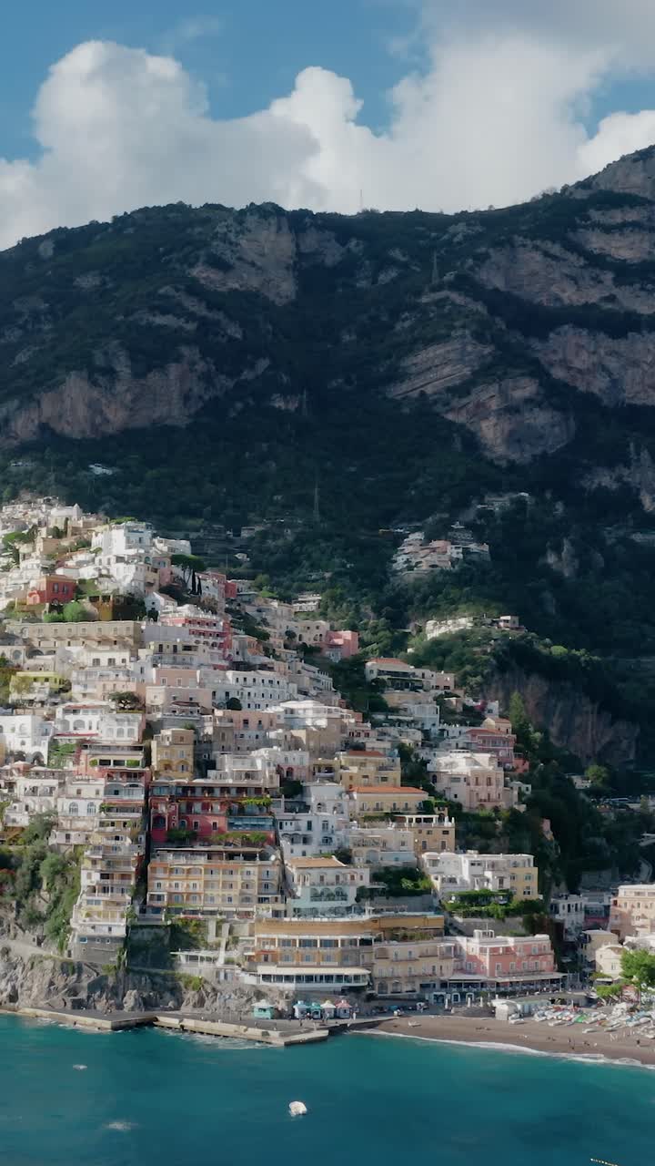 Vertical Panning Aerial View of Italy's Most Iconic and Picturesque Amalfi Coast Town in Campania. Positano Village with Pastel-colored Houses on a Cliffside with Turquoise Water Beachfront