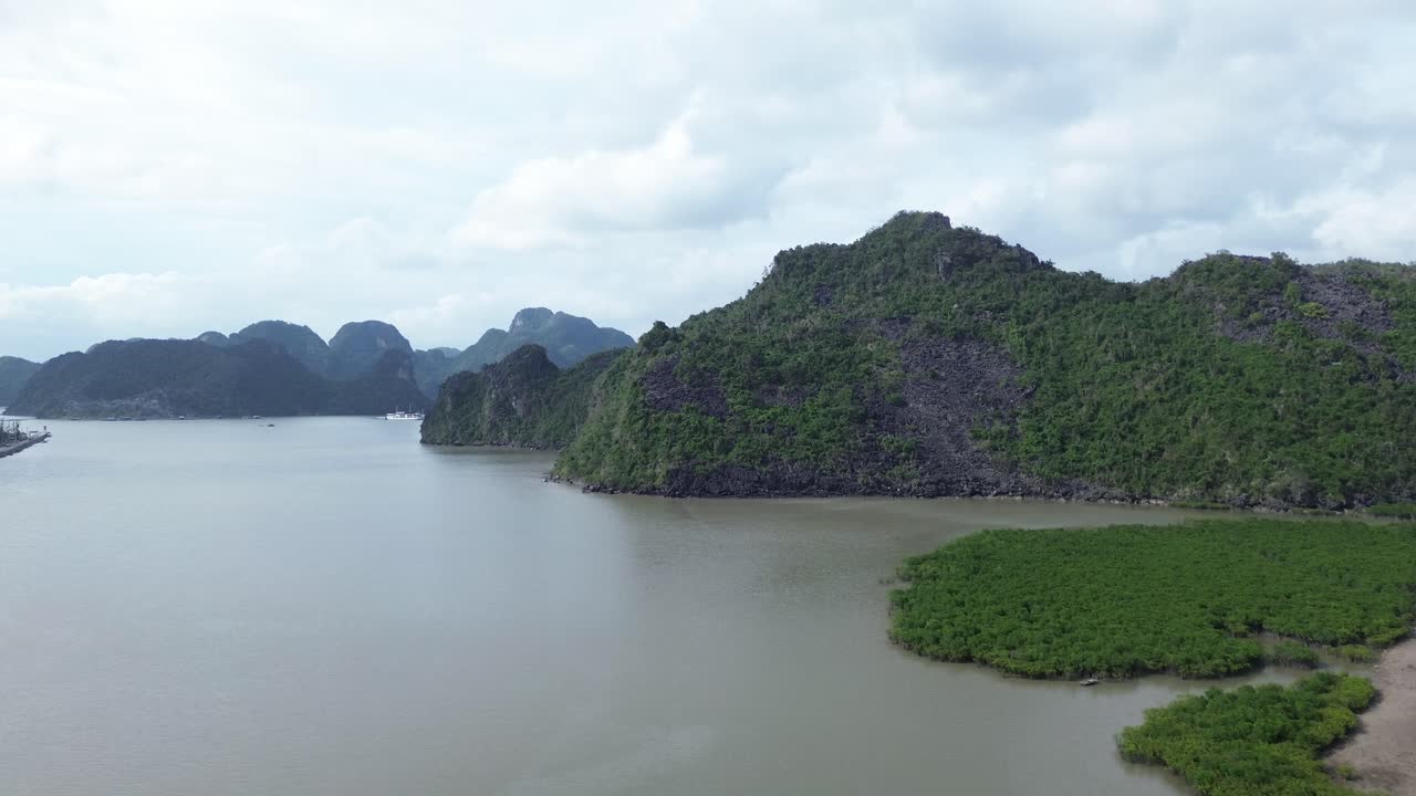 Drone bay về phía trước hé lộ bờ biển đá, những ngọn núi xanh tươi và rừng ngập mặn dày đặc.